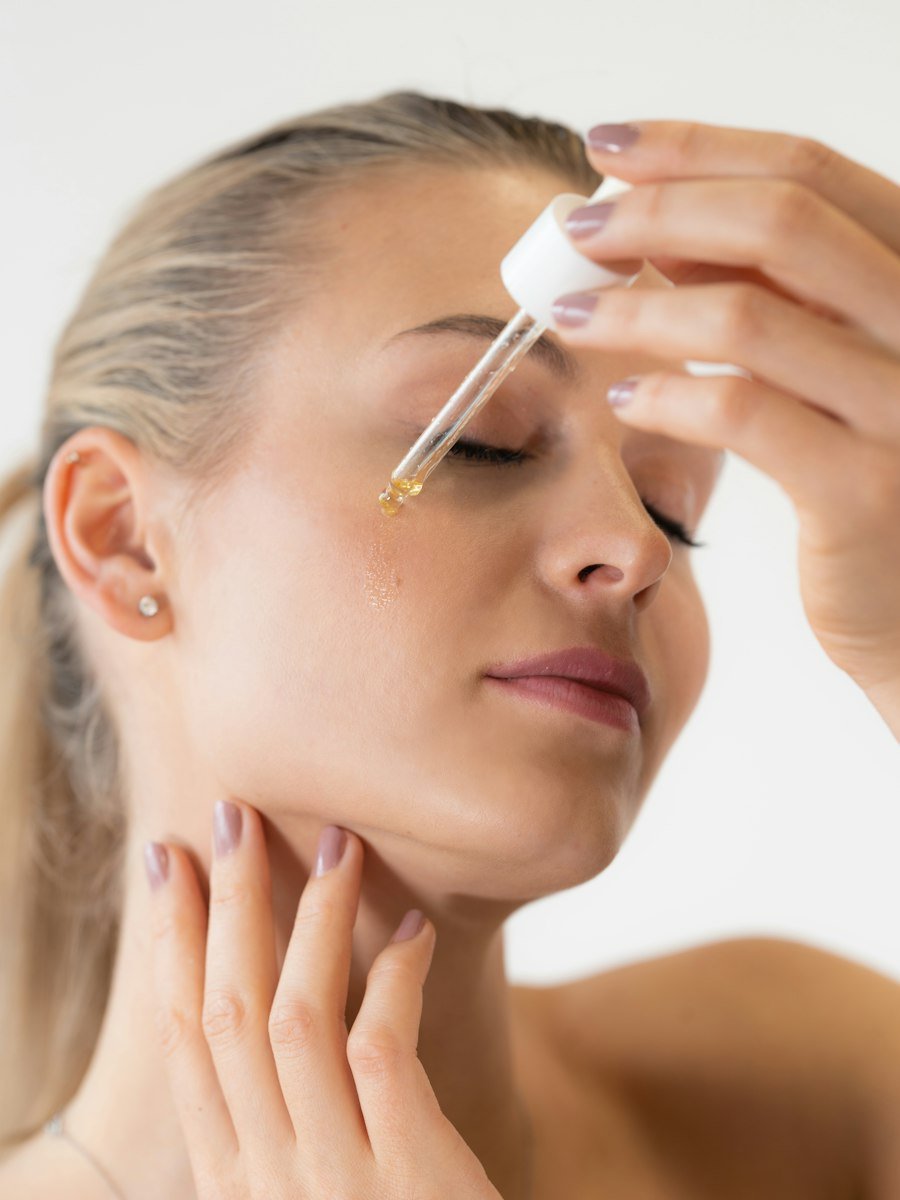 Woman applying facial serum with a glass dropper